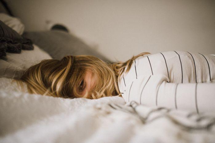 mulher deitada na cama com cara de frustração