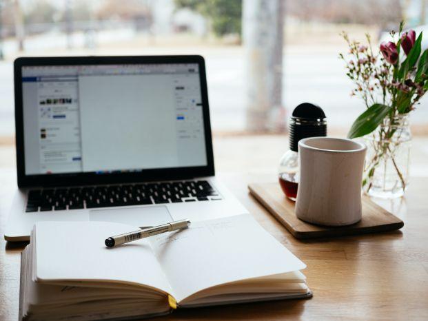 caderno com caneta em frente a computador