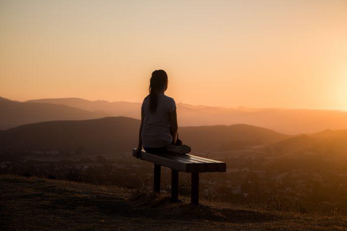 mulher meditando e observando o por do sol