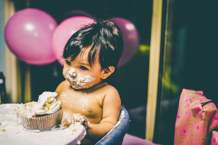 criança comendo e toda suja de bolo de festa